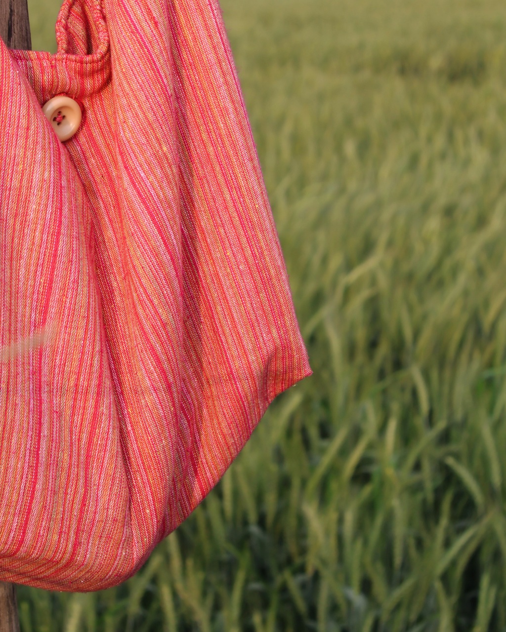 Red and orange striped fabric hanging in a field of green plants