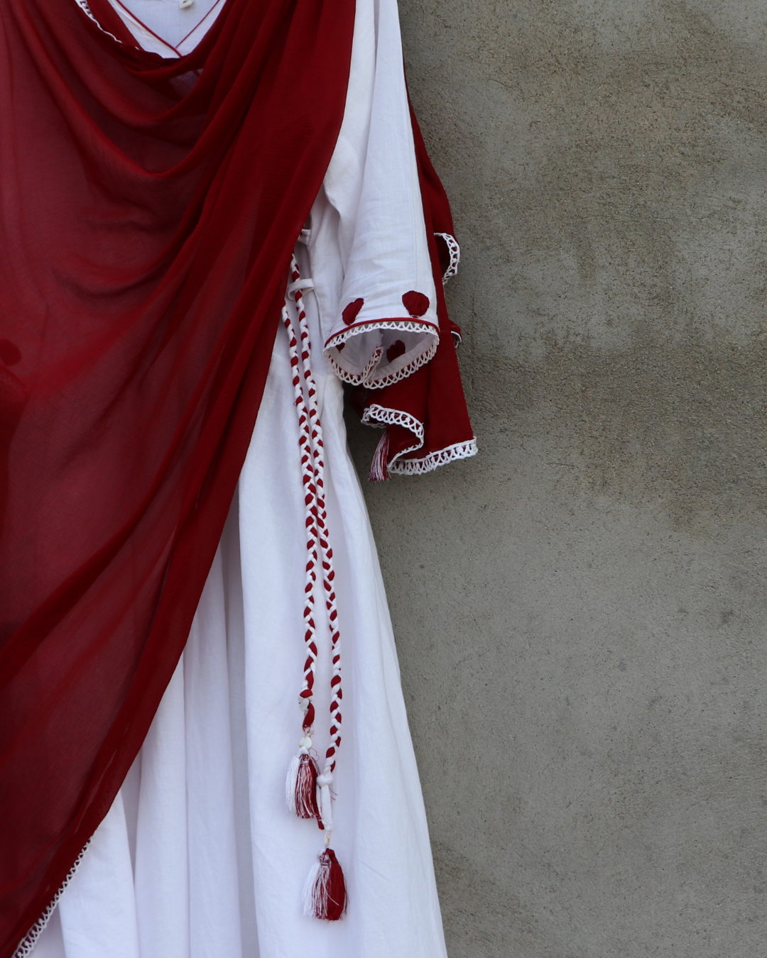 Traditional red and white garment with intricate designs against a neutral background