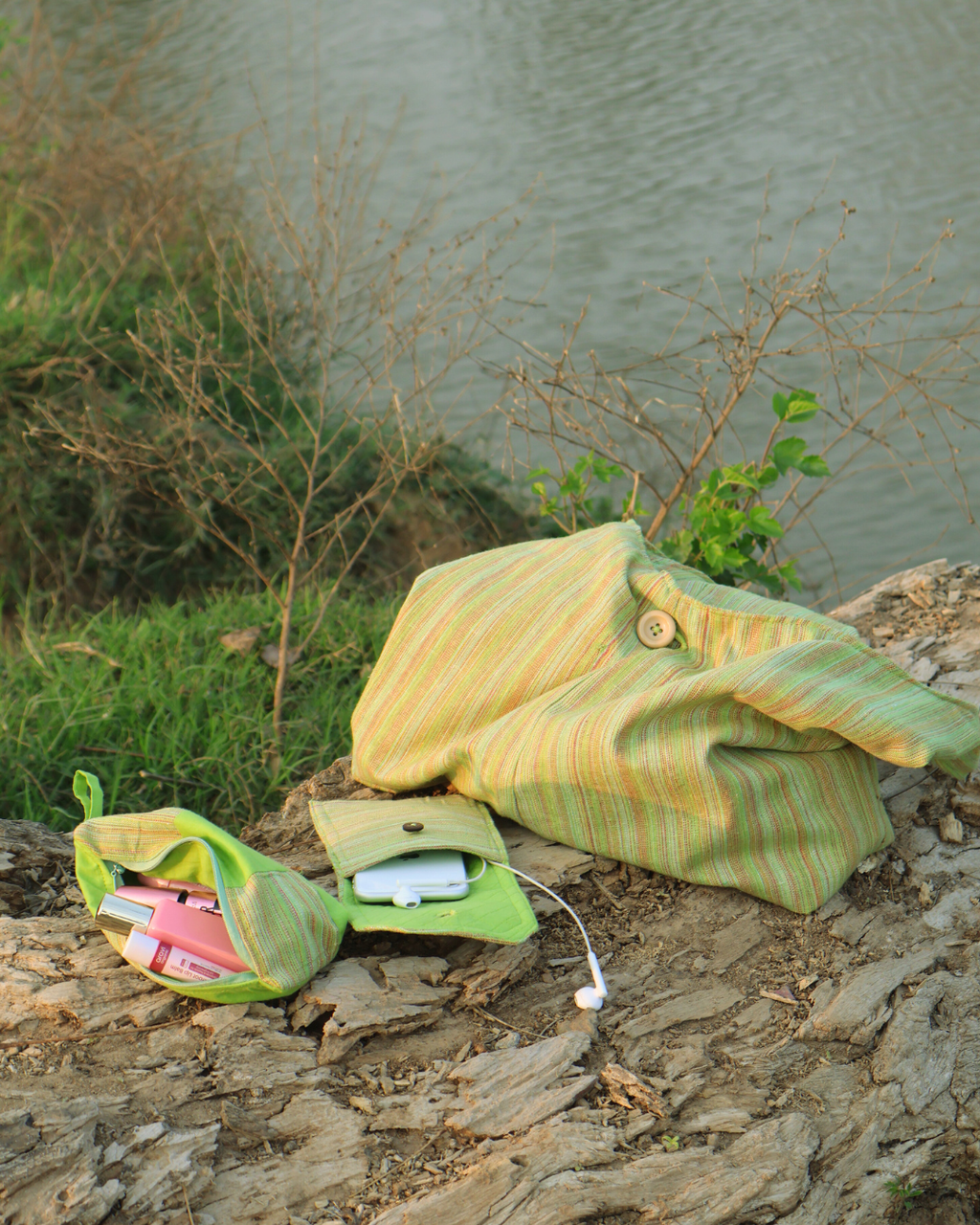 Green and yellow striped fabric bag on a stone surface with a natural background