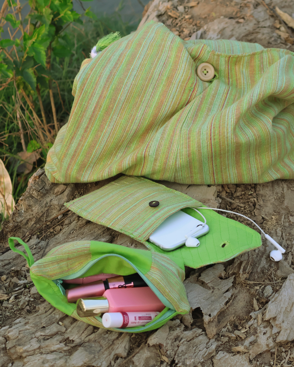 Green striped fabric bag with makeup items on a wooden surface