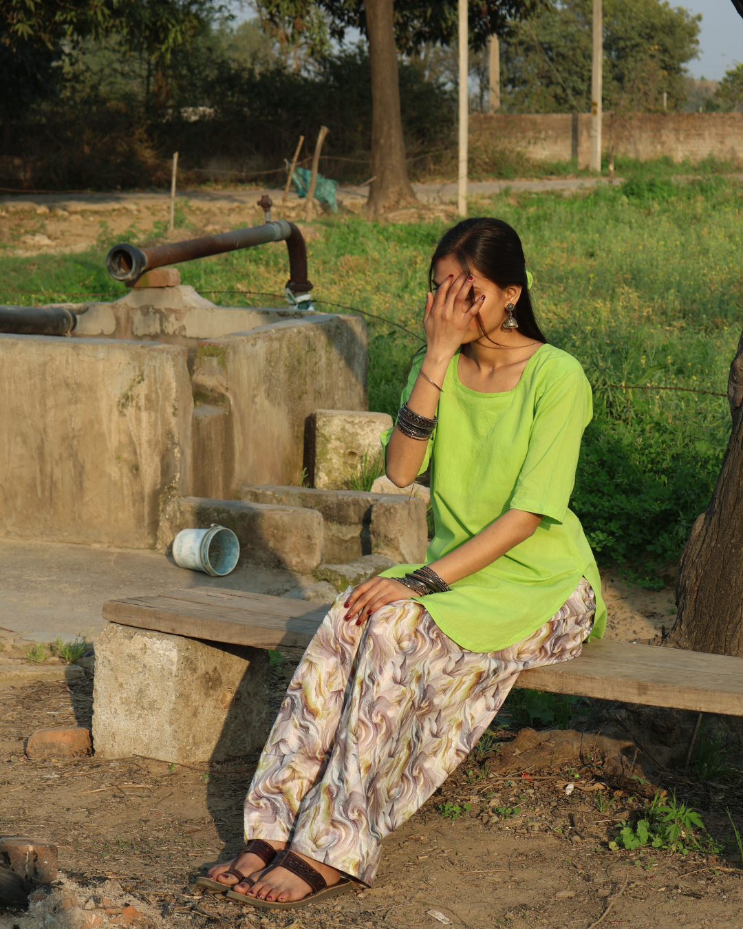 Woman sitting by a well in an outdoor setting