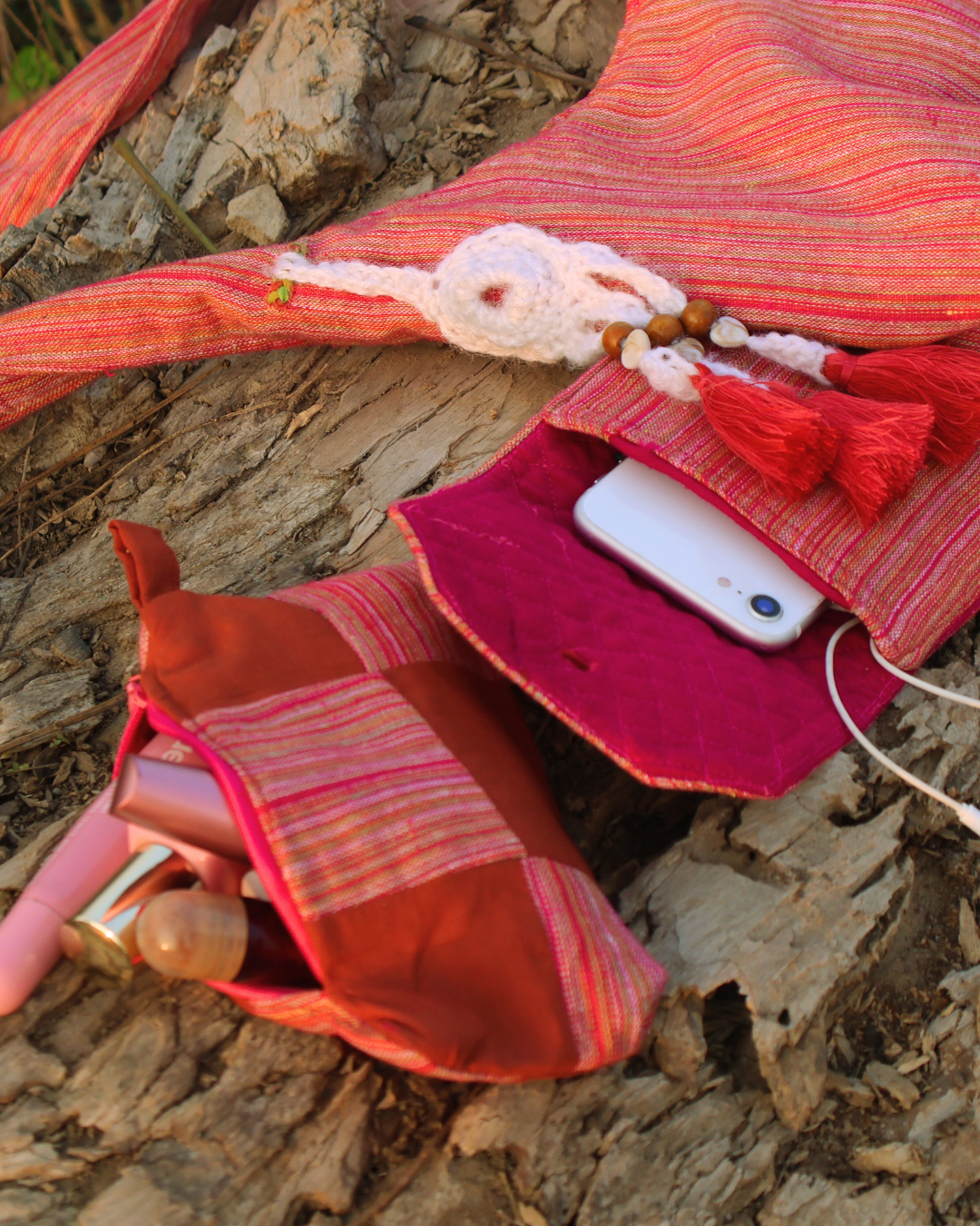 Red fabric pouch with a phone and other items on a stone surface