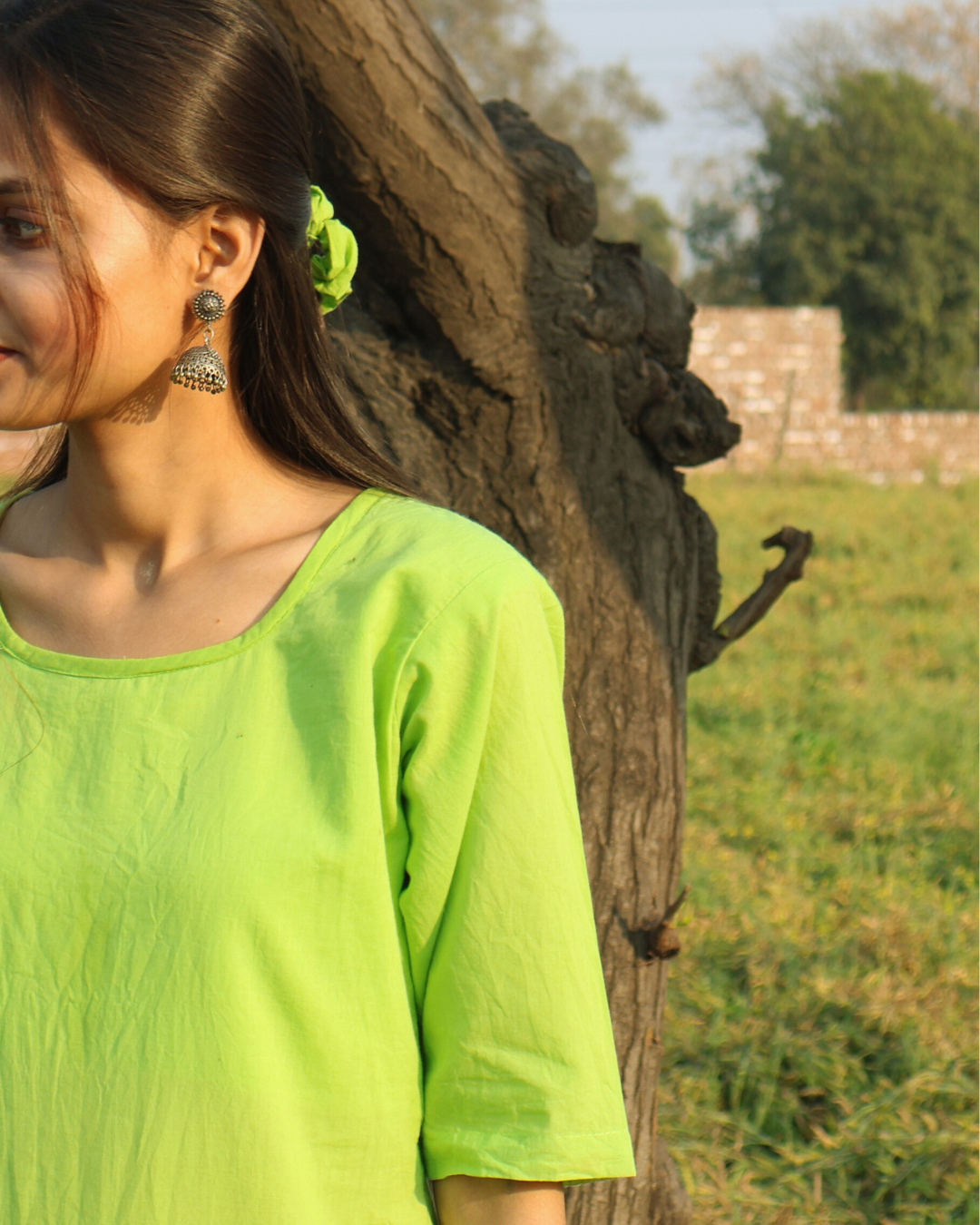 Woman in a green top standing next to a stone sculpture in an outdoor setting