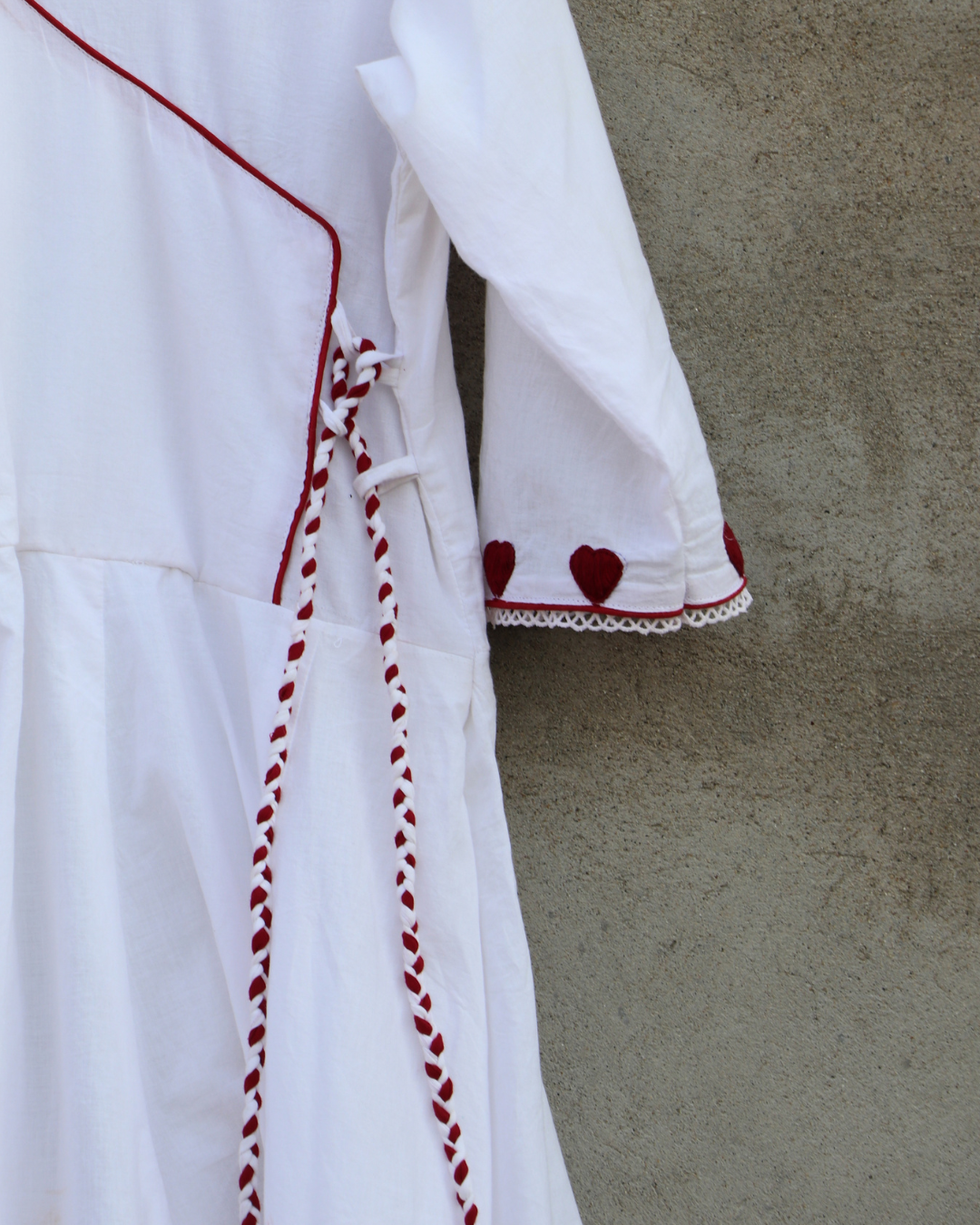 White garment with red accents and heart patterns on a beige background