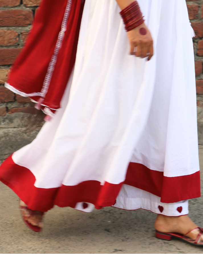 Person wearing a white and red traditional outfit with a brick wall background