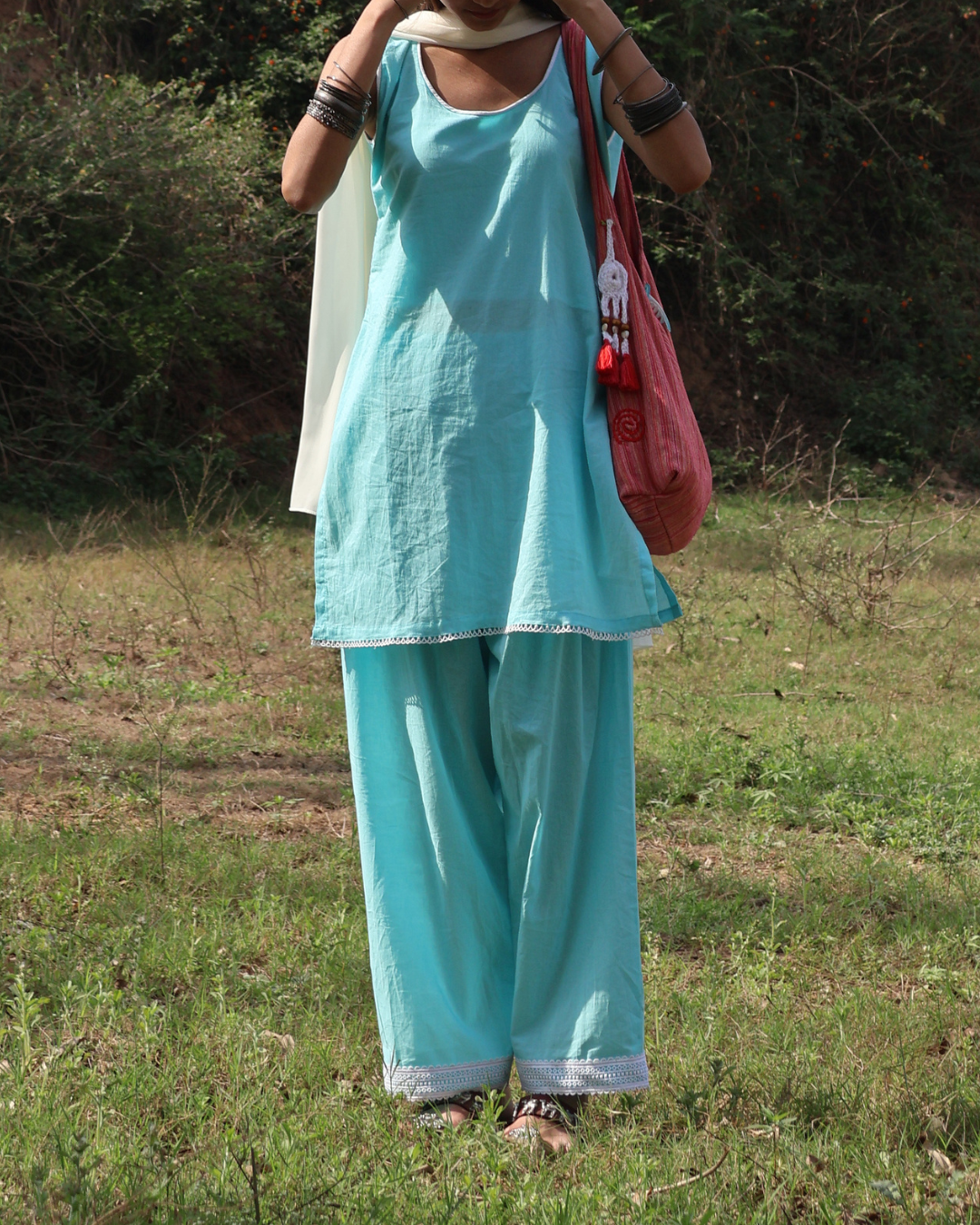 Person wearing a turquoise outfit with wide-leg pants in an outdoor setting