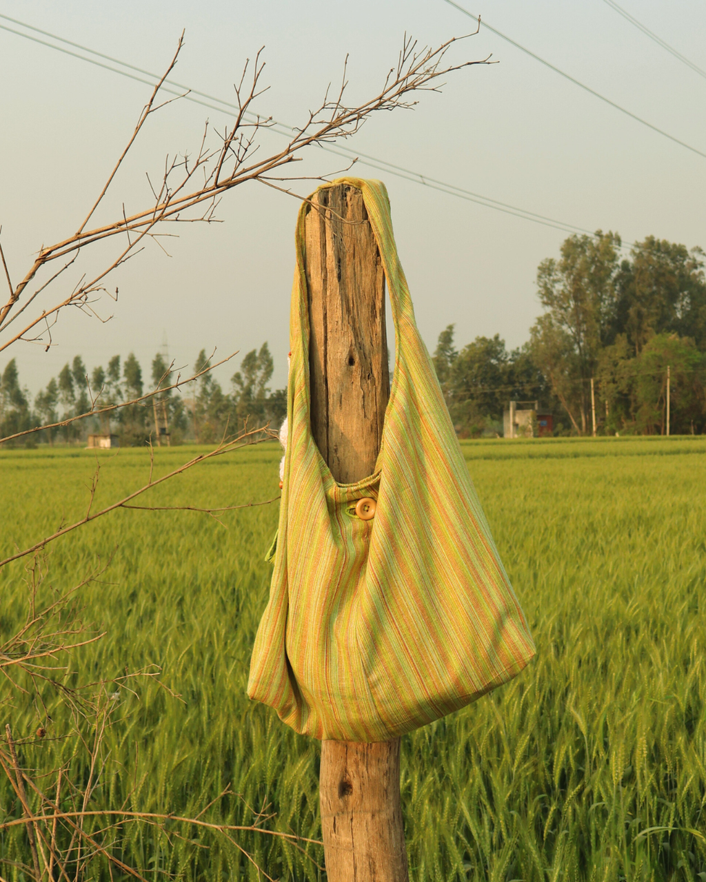 Wooden post with a green and yellow striped cloth draped over it in a field