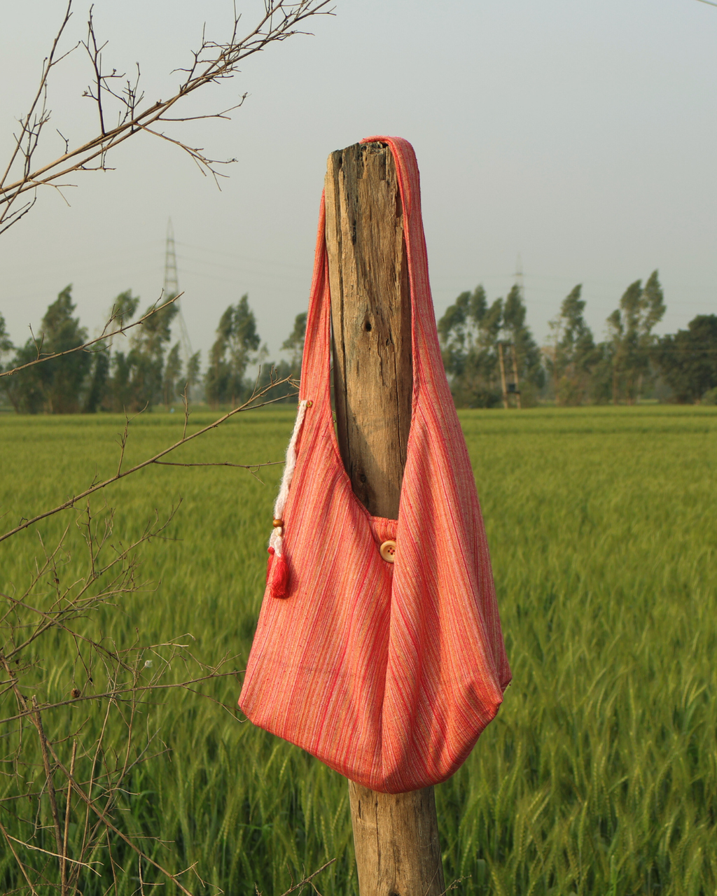 Pink bag hanging on a wooden post in a field with trees in the background