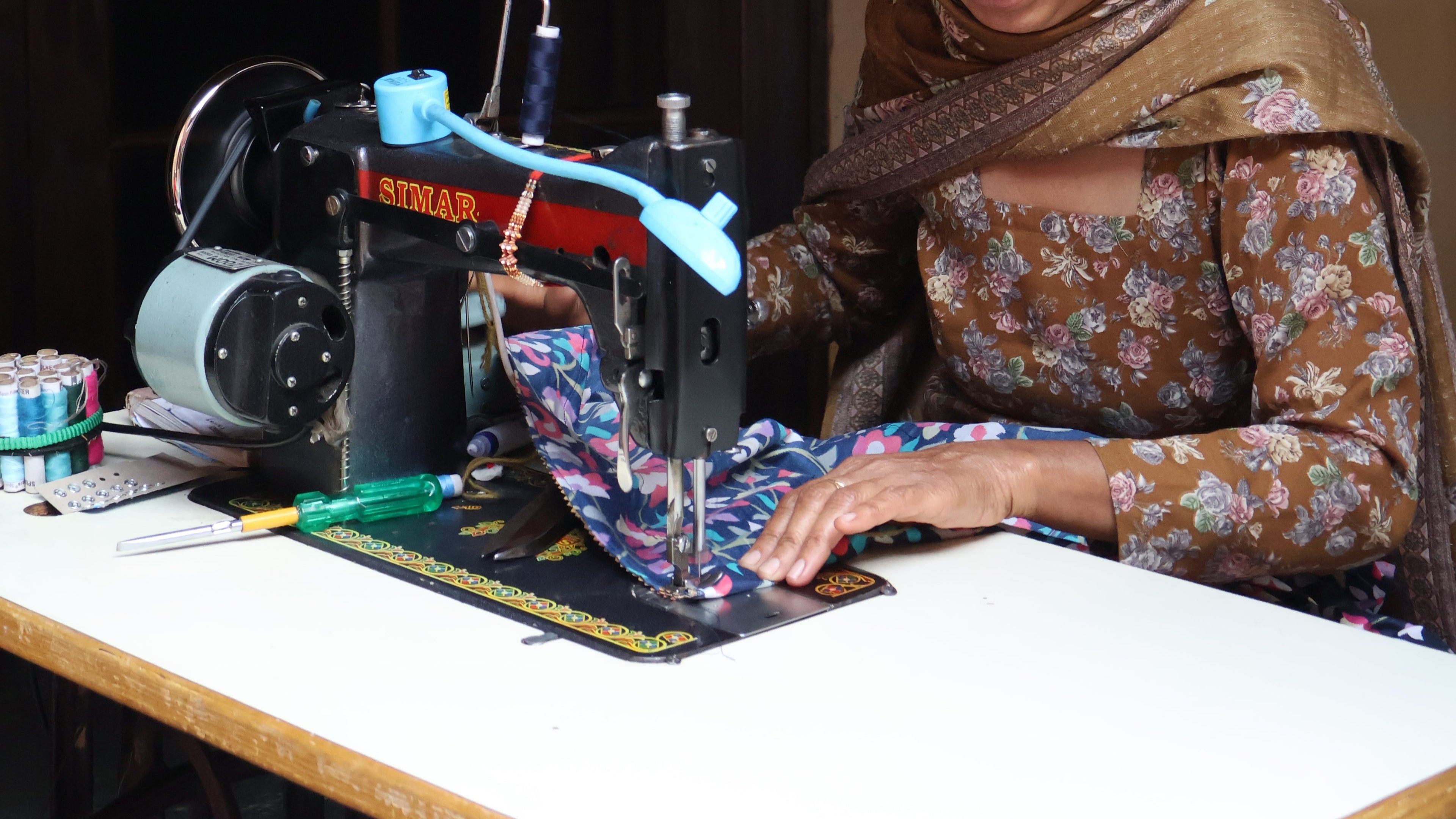 Woman working at a sewing machine in a dimly lit room.